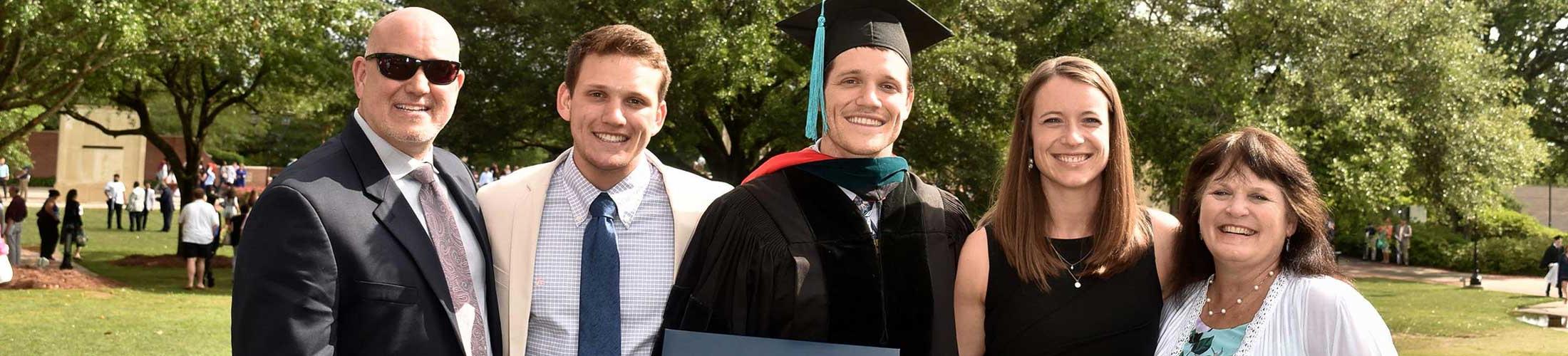 Graduate in cap and gown with family outside